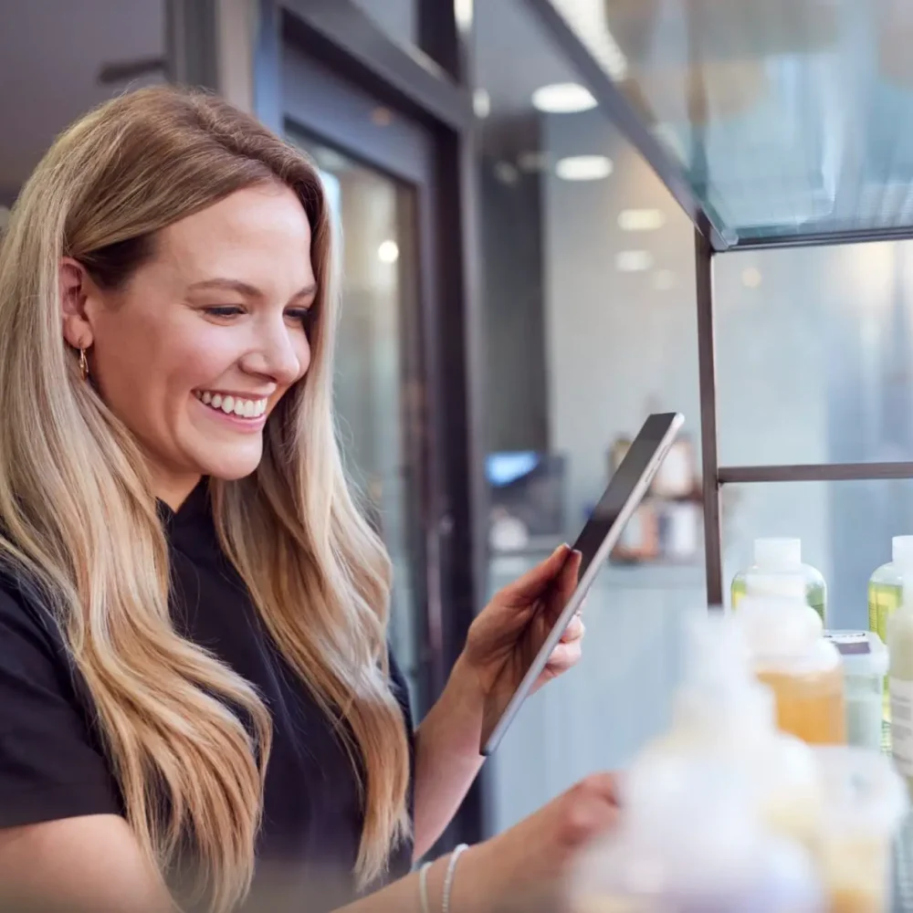 Female Stylist Or Business Owner In Hairdressing Salon Using Digital Tablet To Check Beauty Products Female Stylist Or Business Owner In Hairdressing Salon Using Digital Tablet To Check Beauty Products